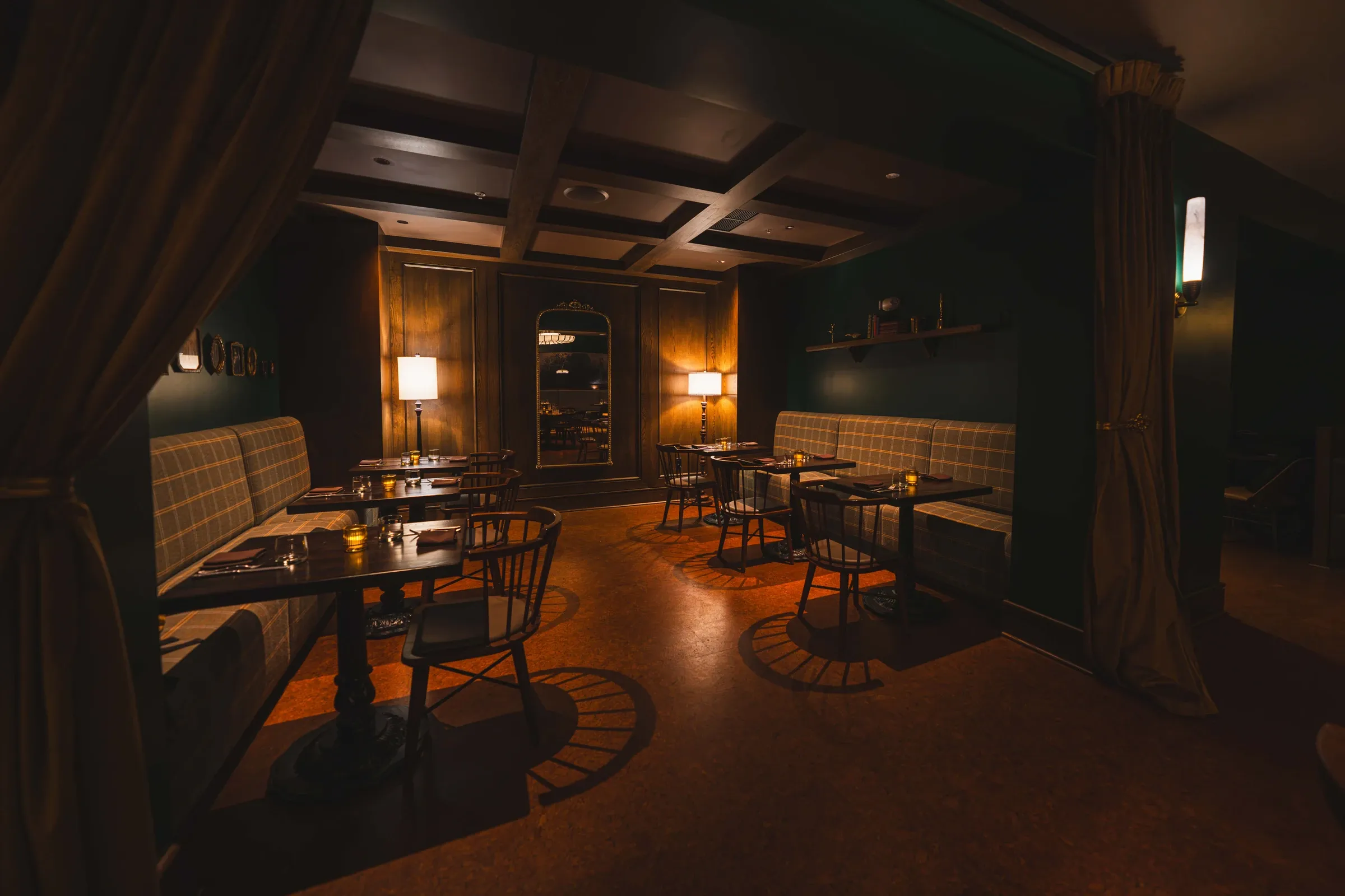 The Nook set for dinner, plaid banquettes along both walls under a coffered ceiling