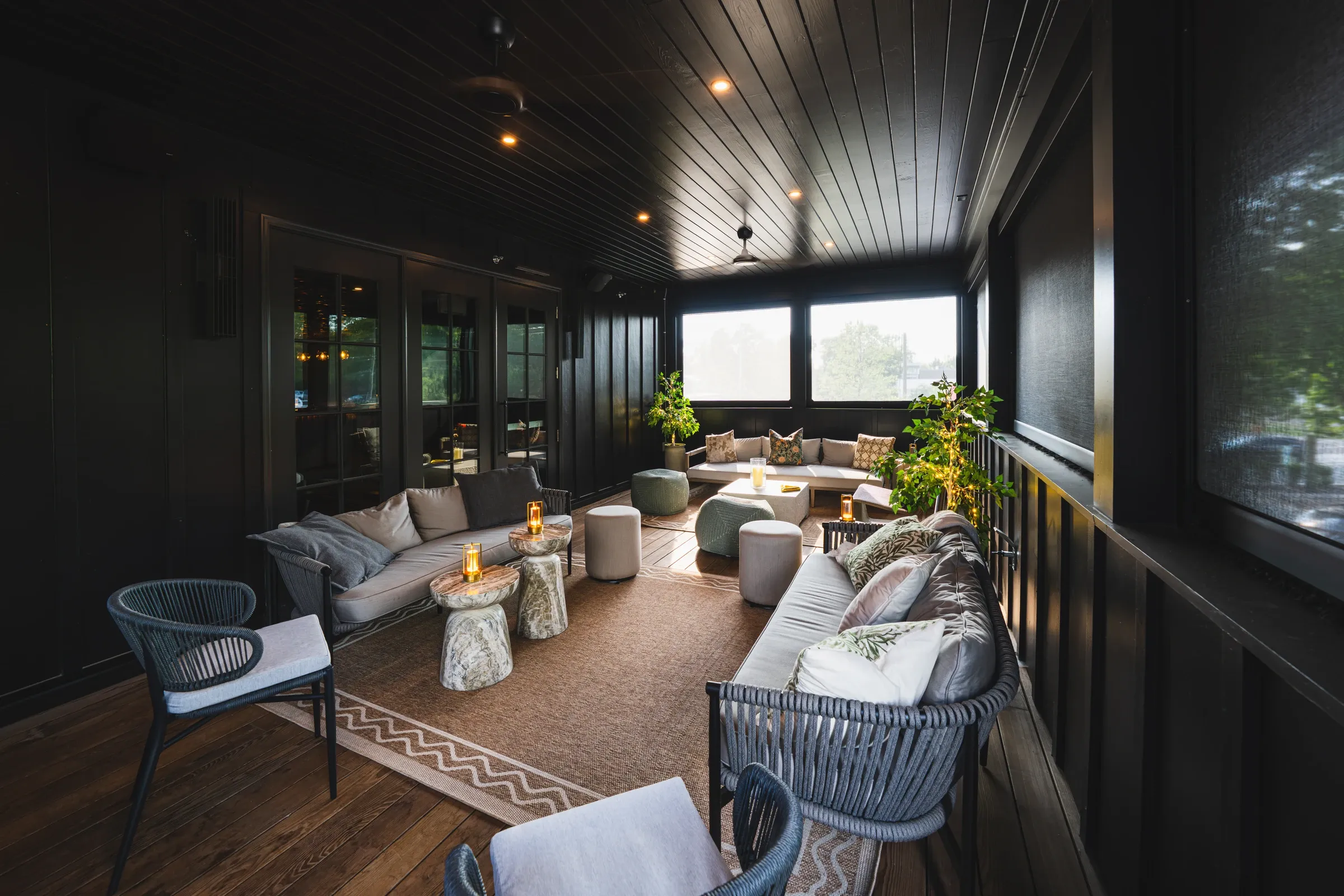 The long upstairs terrace with sofas and lanterns under a dark wood ceiling